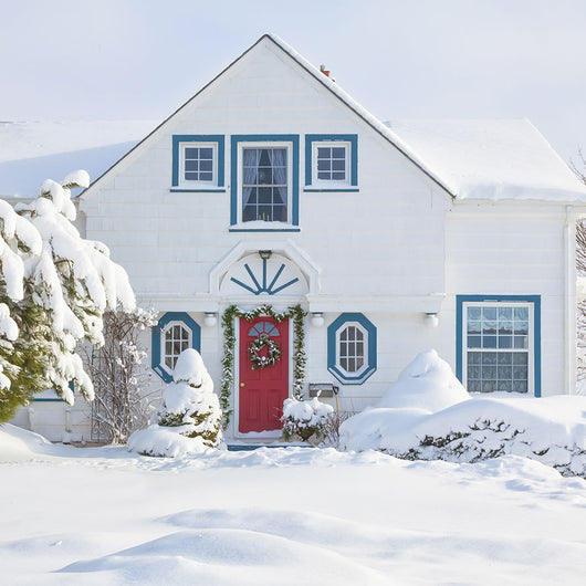 A winter scene with a white house with red door.